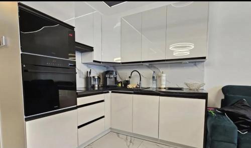 una cucina con armadi bianchi e un apparecchio nero di Apartament De LUX Wrzosowo Dziwnówek a Dziwnówek