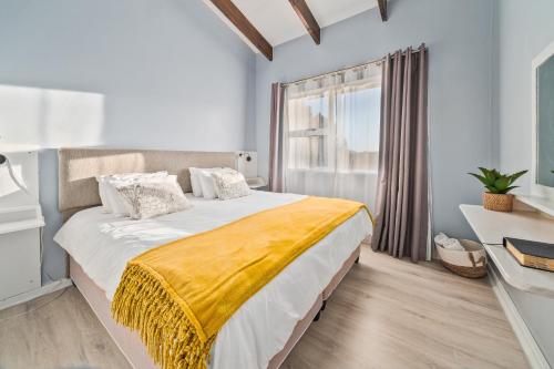 a bedroom with a large bed with a yellow blanket at Stunning Knysna central Apartment in Knysna