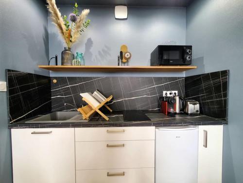 une cuisine avec des armoires blanches et un comptoir noir dans l'établissement Saint Jean - La Rivière- T2 tout neuf, à Niort