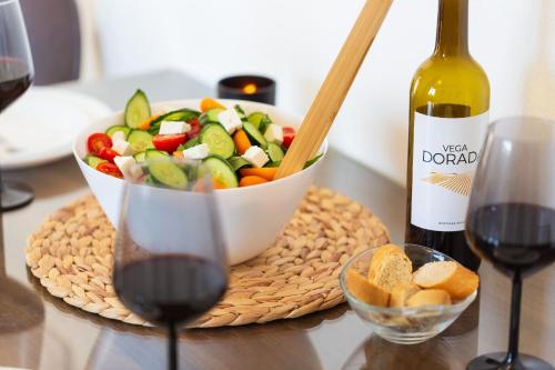a table with a bowl of vegetables and a bottle of wine at Artemis Cynthia Complex in Paphos City