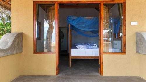 a bedroom with a bed inside of a glass door at Peanut Farm Surf and Wild Resort - Arugambay in Arugam Bay