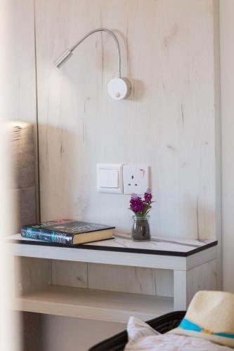 a table with a book and a vase of flowers on it at Artemis Cynthia Complex in Paphos City