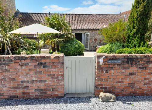a cat sitting next to a brick wall with an umbrella at Luxury Barn near Wells - Pool, Gym in Wells