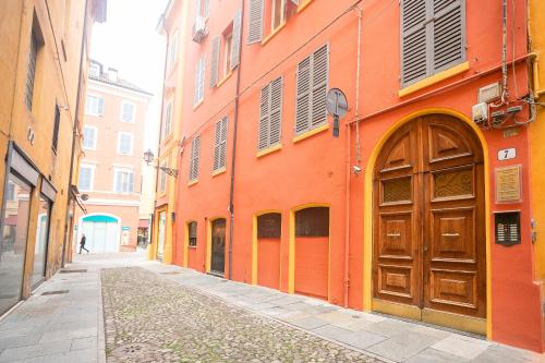 an orange building with a wooden door on a street at Center Vicolo Suite Apartment with Parking in Modena