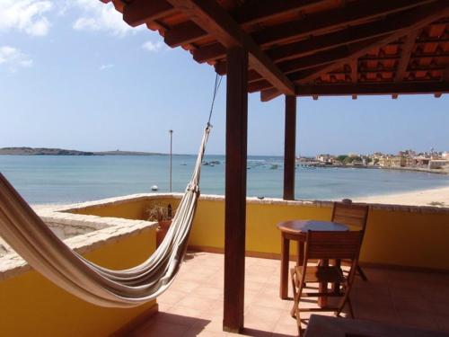 a hammock on a balcony with a view of the beach at Guest House Orquidea in Sal Rei