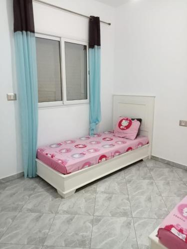 a small bed in a room with blue curtains at DaR GHANDOUR in Hanshīr Qaşr Ghallāb