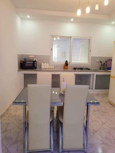 a kitchen with a table and two white chairs at DaR GHANDOUR in Hanshīr Qaşr Ghallāb