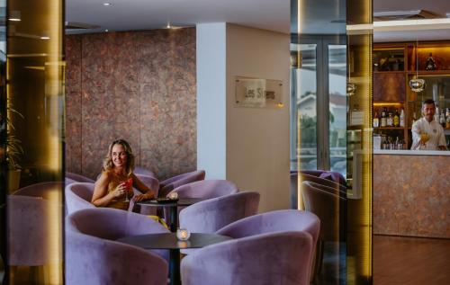 a woman sitting in a restaurant with purple chairs at Lordos Beach Hotel & Spa in Larnaka