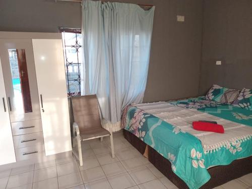 a bedroom with a bed and a chair and a window at Gabade Guest House 2 in KwaDukuza