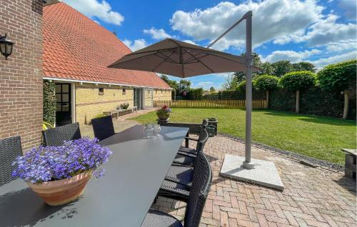a table with an umbrella and flowers on a patio at Nice Home In Oudeschoot With Wifi in Oudeschoot