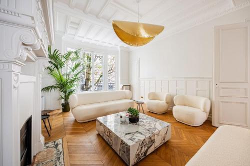 un salon avec des meubles blancs et un lustre doré dans l'établissement Amazing Apartment # 5Bedrooms #Paris 16 #Trocadero, à Paris