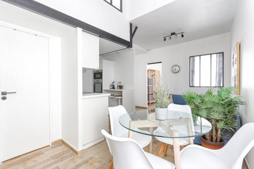 une salle à manger et une cuisine avec une table en verre et des chaises blanches dans l'établissement Résidor - Appartement 4P chaleureux et lumineux !, à Paris