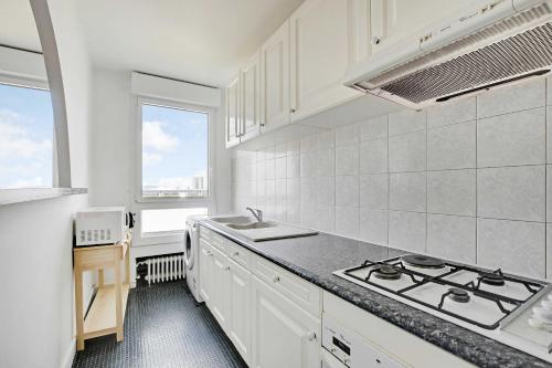 une cuisine avec des armoires blanches et un four à plaques de cuisson dans l'établissement Cosy apartment - 1BR-4P - La Villette, à Paris