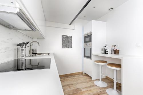 une cuisine blanche avec un comptoir et des tabourets dans l'établissement Résidor - Appartement 4P chaleureux et lumineux !, à Paris