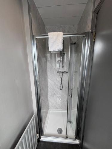 a shower with a glass door in a bathroom at Richmond Park Hotel in Boʼness