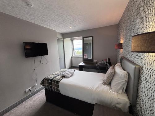 a hotel room with a bed and a television at Richmond Park Hotel in Boʼness