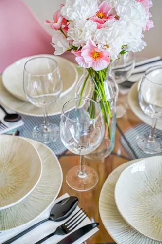 a table with plates and glasses and a vase of flowers at Inn Place to be Paris La Defense in Courbevoie