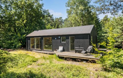 a black tiny house with a deck and chairs at 3 Bedroom Amazing Home In Stege in Stege