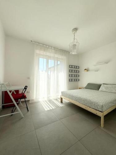 a white bedroom with a bed and a desk at Casa Anna Asciano in Asciano Pisano