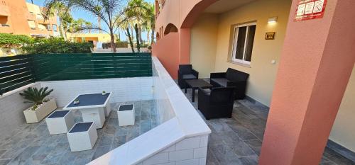 a balcony of a building with tables and chairs at Homes of Spain, Apartamentos Paraiso de Vera Playa, Ed Tahiti bajo H, a pie de la playa, vistas piscina in Vera