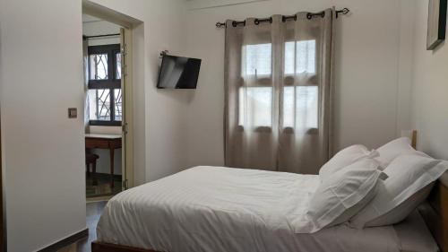 Un dormitorio con una cama con sábanas blancas y una ventana. en Appartement hôtel de luxe 974, en Antananarivo