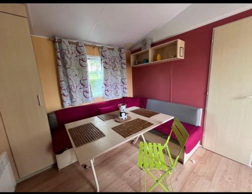 une petite chambre avec une table et un canapé rose dans l'établissement Mobil-home au camping de bairon, à Le Chesne