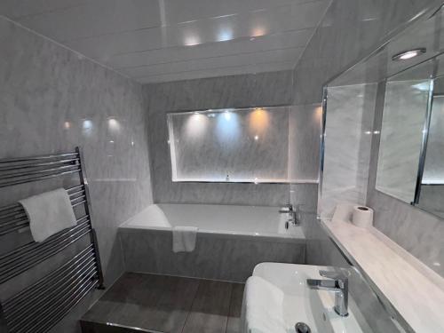 a bathroom with a bath tub and a sink at Richmond Park Hotel in Boʼness