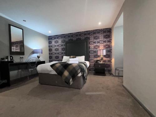 a bedroom with a bed in a room with a brick wall at Richmond Park Hotel in Boʼness