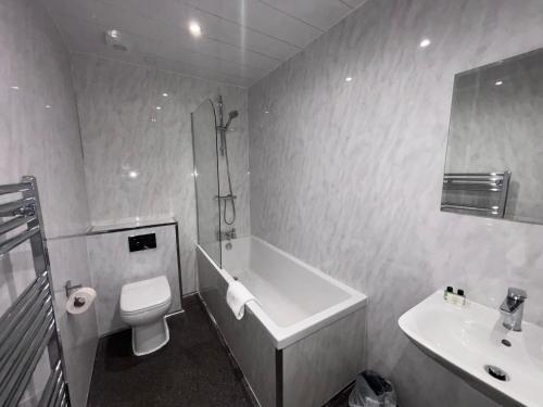 a bathroom with a tub and a toilet and a sink at Richmond Park Hotel in Boʼness