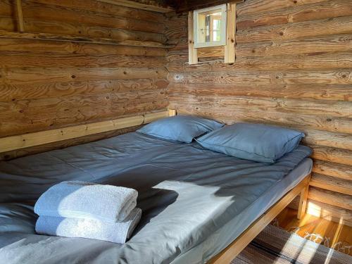 een bed in een blokhut met een raam bij Metsäsydän mökki 4 Mettäpöyröö in Puumala
