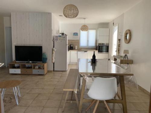 eine Küche und ein Wohnzimmer mit einem Tisch und einem Kühlschrank in der Unterkunft Maison de vacance proche de la plage in La Brée-les-Bains