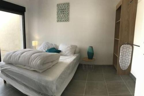 Schlafzimmer mit einem Bett mit weißer Bettwäsche und einem Tisch in der Unterkunft Maison de vacance proche de la plage in La Brée-les-Bains