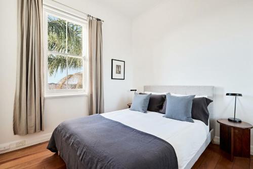 a white bedroom with a bed and a window at Coogee Treetops in Sydney