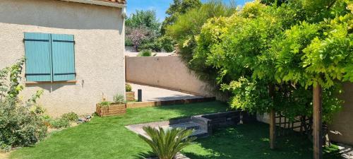 a backyard of a house with a green yard at Villa accueillante entre Aix et Marseille in Vitrolles