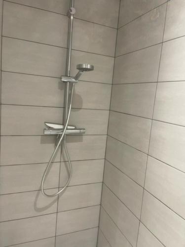 une douche avec un tuyau suspendu à un pommeau de douche dans l'établissement Logement entier Montigny-les-Cormeilles - Près de Paris, à Montigny-lès-Cormeilles