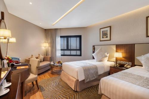 a hotel room with two beds and a couch at The Oberoi Madina المدينة أوبروي in Al Madinah