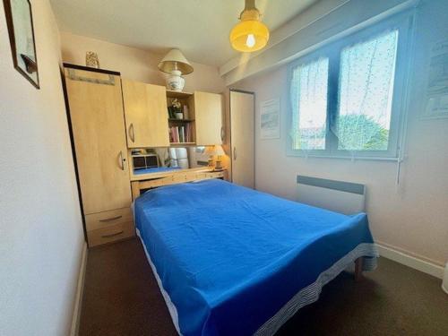 a small bedroom with a blue bed and a window at Quiberon - Appartement 2 pièces - 4 pers - Calme - Parking - FR-1-478-73 in Quiberon