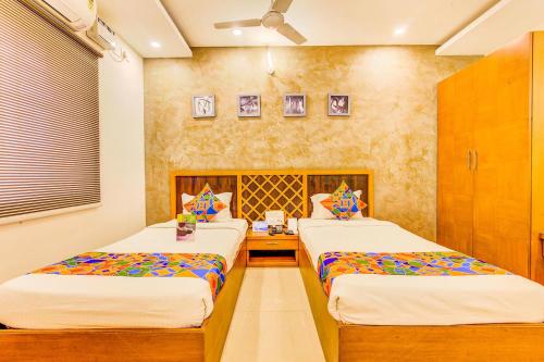 a bedroom with two beds and a desk at FabExpress Mayuri Residency in Bangalore