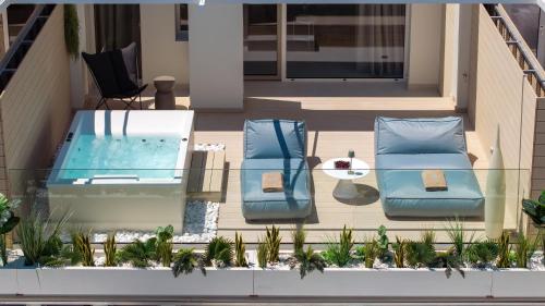 a balcony with a pool and two chairs and a table at Flisvos Royal Hotel & Suites in Tolo