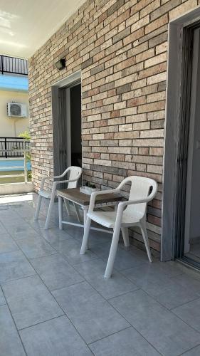 two white chairs and a table on a brick wall at Alice Apartment in Olympiaki Akti