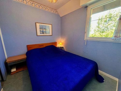 une chambre avec un lit bleu et une fenêtre dans l'établissement Quiberon : Charmant T2 avec piscine, terrasse, parking, proche plage - 4 pers. - FR-1-478-174, à Quiberon