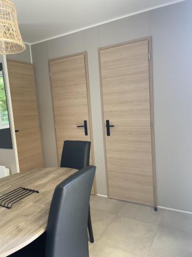 a dining room with wooden doors and a table and chairs at Camping Le Mont César in Gouvieux