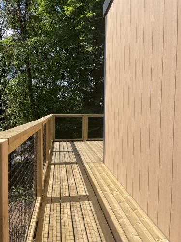 a wooden boardwalk leading to a building with a fence at Camping Le Mont César in Gouvieux