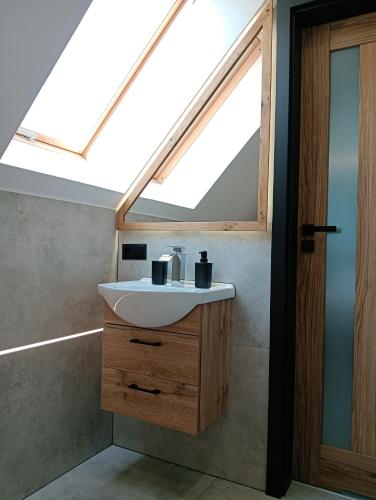 a bathroom with a sink and a skylight at Noclegi SKORUSINKA in Witów
