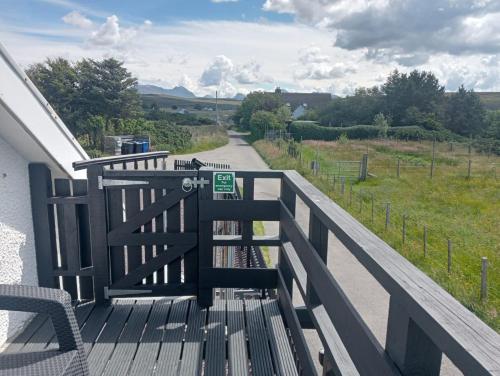 a wooden deck with a bench and a road at Self Catering Spacious open plan 3 bed apartment with sea views in South Erradale