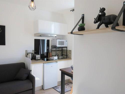 une cuisine avec des armoires blanches, une table et un canapé dans l'établissement Studio rénové avec WIFI, à 400m de la plage, centre de Trégastel - FR-1-368-299, à Trégastel