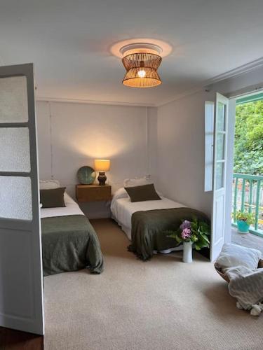 a bedroom with two beds and a chandelier at Casona típica cántabra cerca de la playa de Gerra in La Revilla