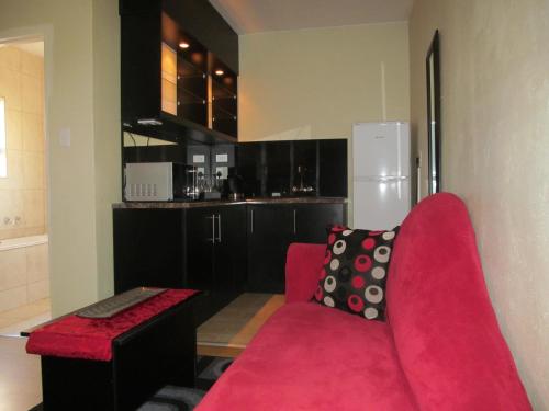 a living room with a red couch and a kitchen at Scenery Maqalika Guesthouse in Maseru