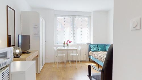 Cette chambre blanche dispose d'une table et d'un lit. dans l'établissement Le Charme Colmarien - Appartement 2 pièces au cœur de la ville, à Colmar