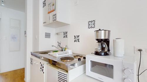 une cuisine blanche avec un micro-ondes et un mixeur dans l'établissement Le Charme Colmarien - Appartement 2 pièces au cœur de la ville, à Colmar